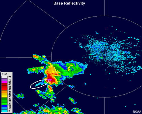 A large thunderstorm with a core containing 75+ dBZ values with a protruding, narrow line of weak reflectivity extending downrange of the radar.